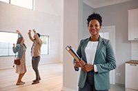 Lavallette real estate agent in foreground and happy couple in new home in background
